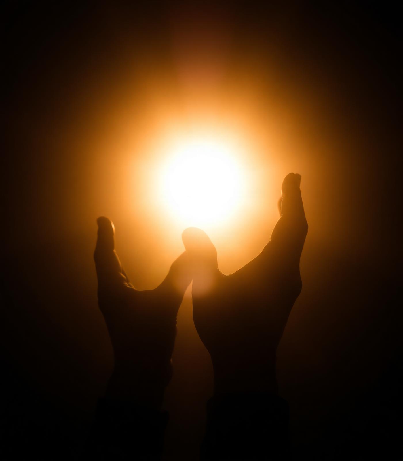 Hands lifted toward golden light